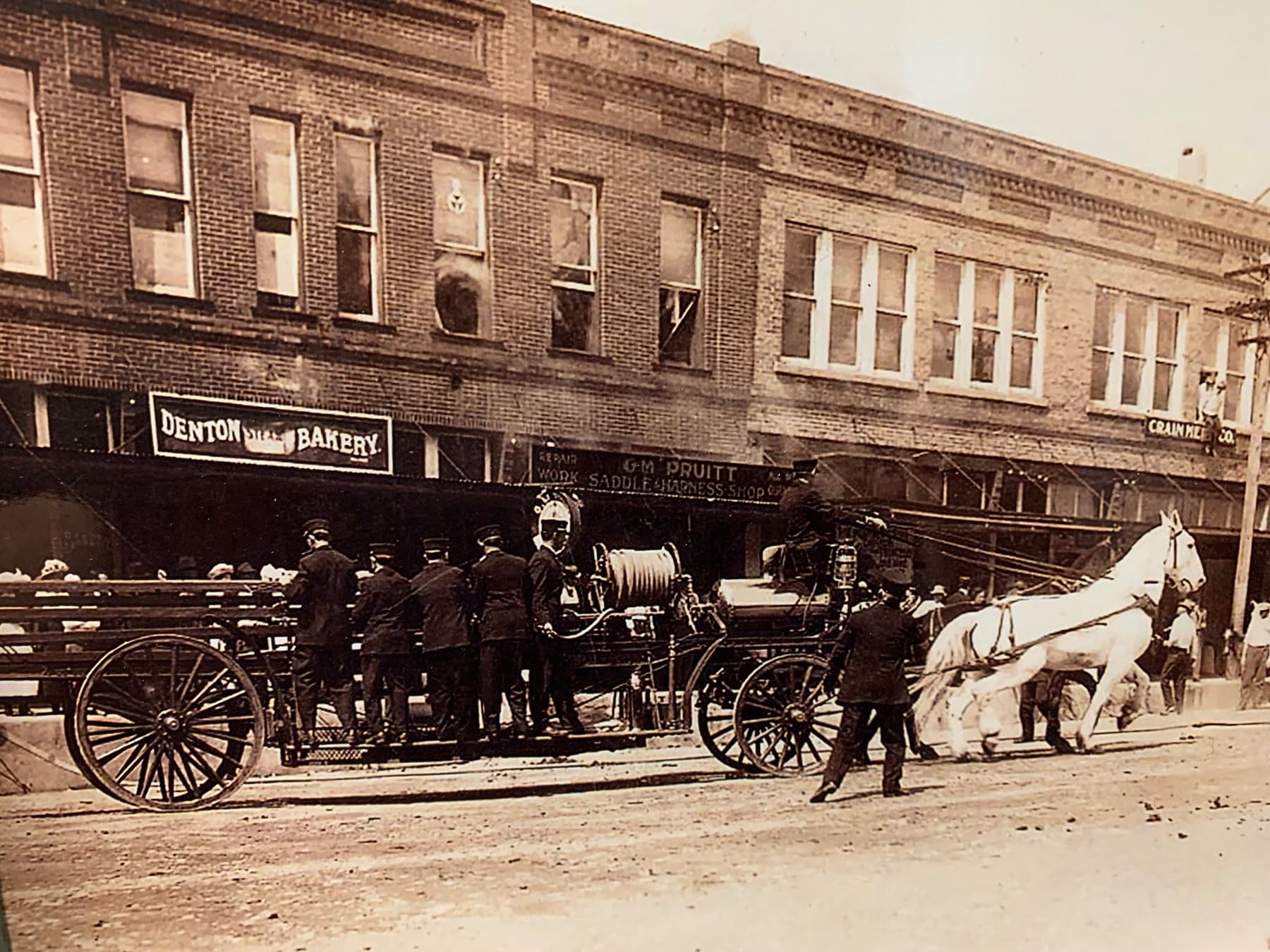 Denton firefighters arriving with horse-drawn equipment at a fire above a bakery